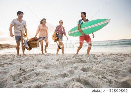 Friends carrying a surfboard and basket 32300366
