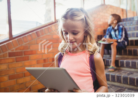 Cute little schoolgirl looking at her digital tablet Cute little schoolgirl looking at her digital tablet 32301039