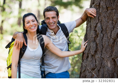 Couple smiling and resting against a tree 32302831