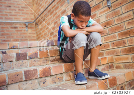 Sad schoolboy with his head on his knee Sad schoolboy with his head on his knee 32302927