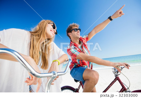 Couple posing with bike on the beach Couple posing with bike on the beach 32303000