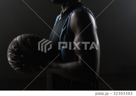 Zoom on a side of a basketball player holding a basketball Zoom on a side of a basketball player holding a basketball 32303383