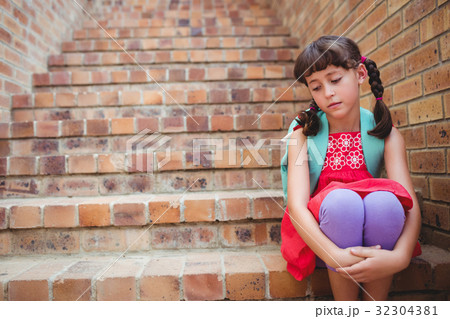 Sad schoolgirl siting in stairs 32304381