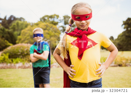 Young girl with superhero dress posing in front of a young boy disguised too 32304721