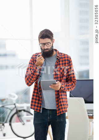 Hipster using tablet while standing Hipster using tablet while standing 32305056