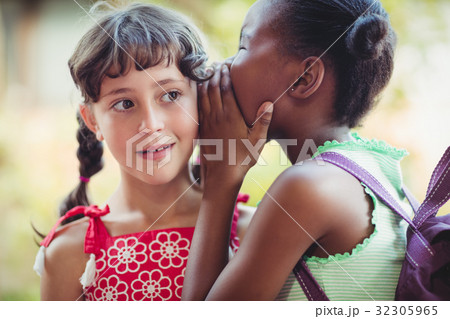 Girl telling a secret to her friend 32305965