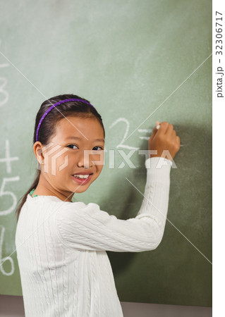 Girl writing with chalk on blackboard Girl writing with chalk on blackboard 32306717