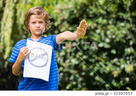 Serious boy saying stop with his hand and holding a message 32307057