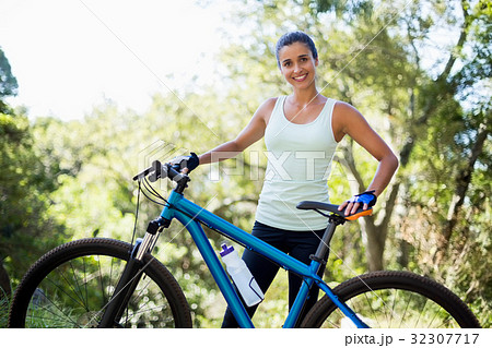 Woman smiling and posing with her bike Woman smiling and posing with her bike 32307717