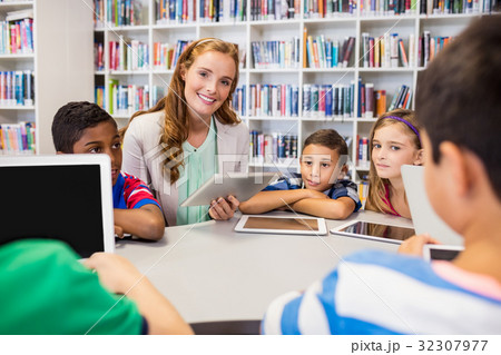 Young pretty teacher having lesson to children with their tablet Young pretty teacher having lesson to children with their tablet 32307977