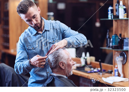 Serious professional hairdresser being involved in 32323500