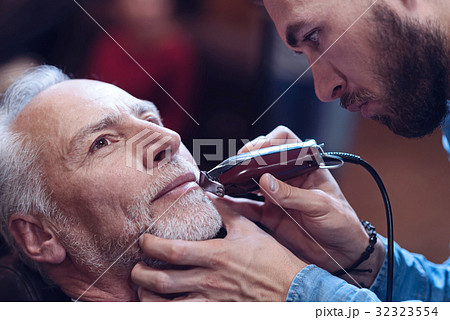 Delighted nice man having his beard trimmed Delighted nice man having his beard trimmed 32323554