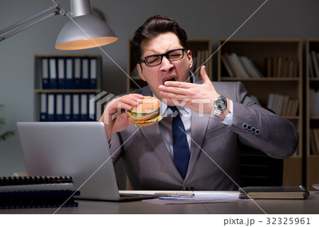 Businessman late at night eating a burger 32325961