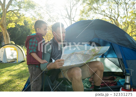 Father and son looking at map outside the tent Father and son looking at map outside the tent 32331275