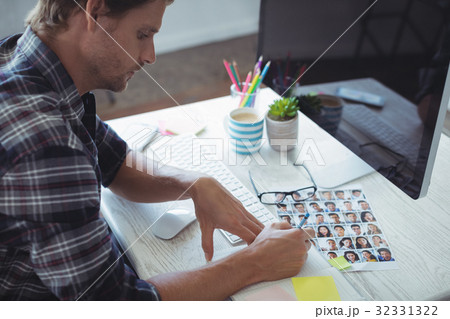 Serious businessman writing in book at creative office desk Serious businessman writing in book at creative office desk 32331322