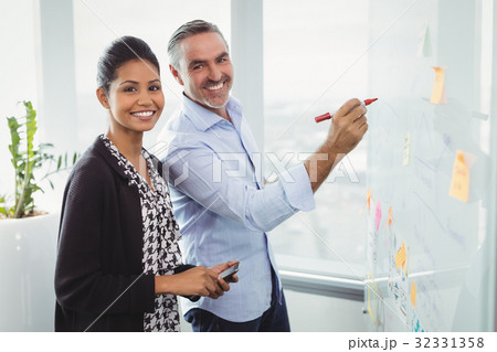 Portrait of smiling colleagues writing on sticky note Portrait of smiling colleagues writing on sticky note 32331358