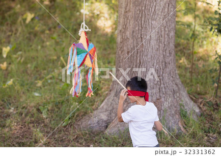 Blindfolded boy hitting pinata in forest Blindfolded boy hitting pinata in forest 32331362