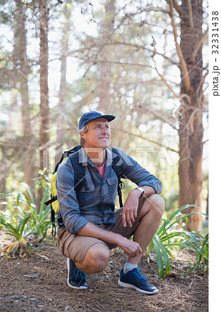 Happy hiker kneeling against trees Happy hiker kneeling against trees 32331438