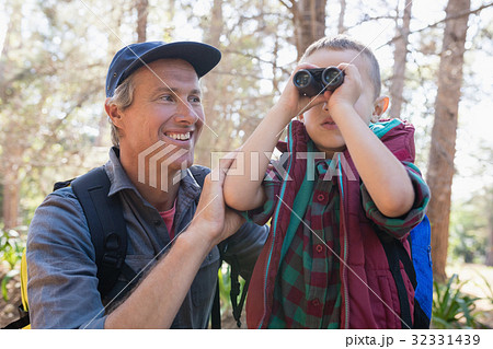 Happy man watching son looking through binoculars Happy man watching son looking through binoculars 32331439