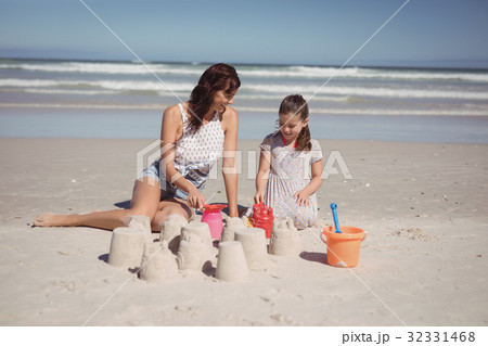 Happy girl with mother making sand castle at beach 32331468