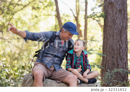 Father and son sitting on rock while pointing away Father and son sitting on rock while pointing away 32331652
