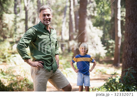 Father and son with hands on hips standing in forest 32332071