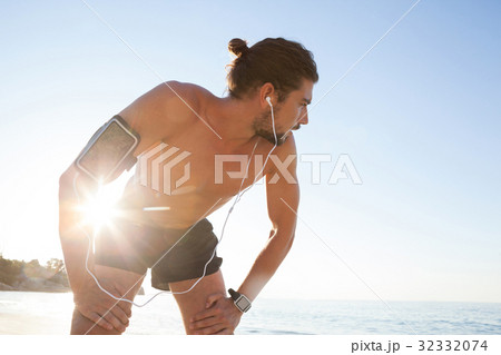 Exhausted man taking a break after jogging on beach 32332074