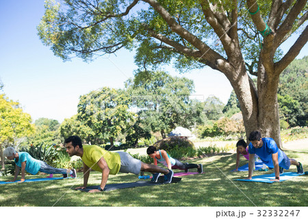 Group of people performing push ups in the park 32332247