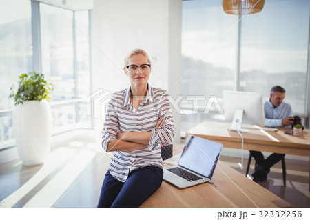 Portrait of confident executive sitting with arms crossed on desk 32332256