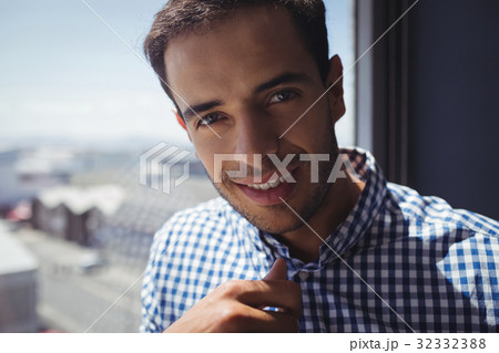 Portrait of young businessman by window in office 32332388