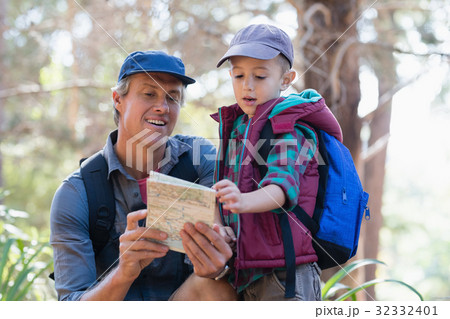 Man and boy reading map in forest 32332401