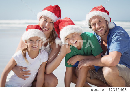 Portrait of happy family wearing Santa hat at beach Portrait of happy family wearing Santa hat at beach 32332463