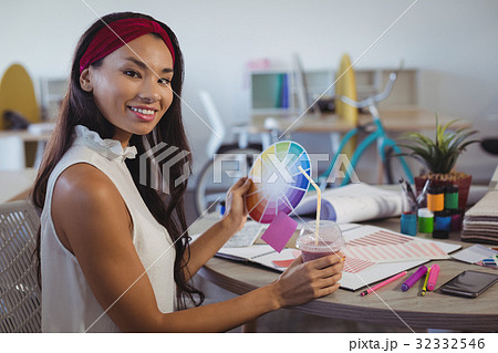 Portrait of businesswoman holding colour swatch and drink at office 32332546