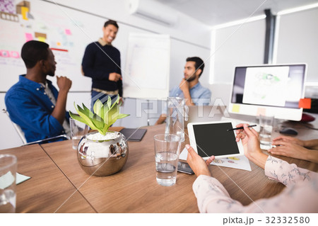Cropped image of businesswoman using digital tablet while colleagues discussing in meeting room Cropped image of businesswoman using digital tablet while colleagues discussing in meeting room 32332580