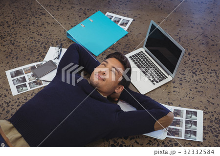 Thoughtful businessman lying by laptop and photographs at office Thoughtful businessman lying by laptop and photographs at office 32332584