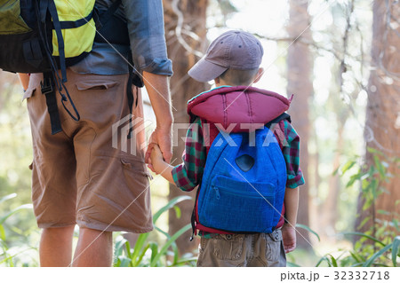 Rear view of boy holding hands with father in forest Rear view of boy holding hands with father in forest 32332718