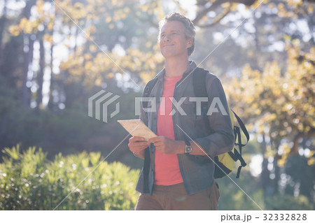 Happy male hiker standing with digital tablet in forest 32332828