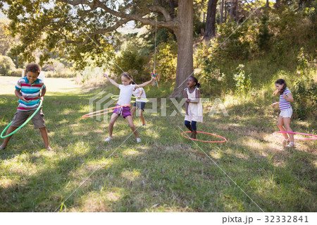 Group of friends playing with hula hoops at campsite 32332841