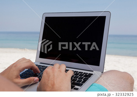 Man using laptop while resting at beach Man using laptop while resting at beach 32332925