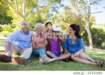 Girl using vr headset while sitting with her family Girl using vr headset while sitting with her family 32333066