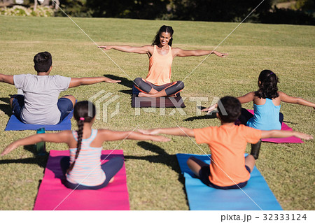 Happy trainer teaching stretching exercise to children 32333124