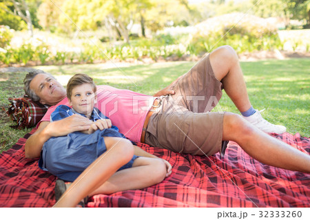 Father and son lying on picnic blanket in park 32333260