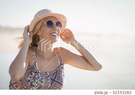 Young woman wearing sunglasses and hat at beach 32333262