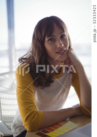 Portrait of businesswoman leaning on desk at office 32333425