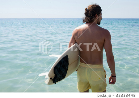 Surfer with surfboard looking at sea from the beach 32333448