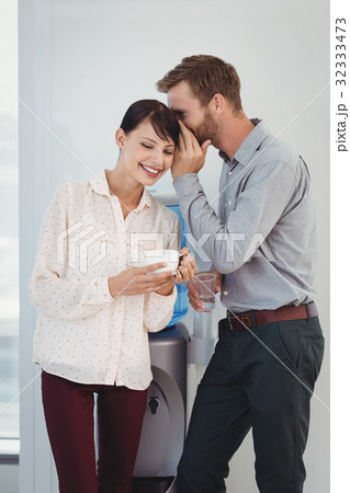 Man whispering in his colleagues ear 32333473