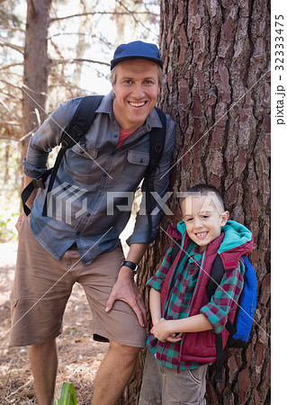 Portrait of happy father and son leaning on tree trunk Portrait of happy father and son leaning on tree trunk 32333475