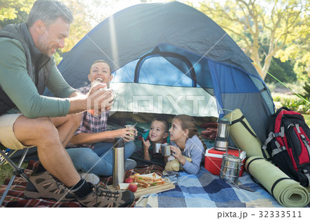 Family interacting while having snacks outside the tent Family interacting while having snacks outside the tent 32333511