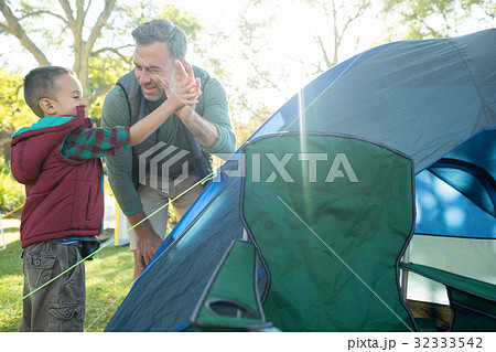 Father and son giving a high five after setting up the tent Father and son giving a high five after setting up the tent 32333542