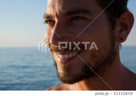 Close up of smiling man looking away at beach 32333659